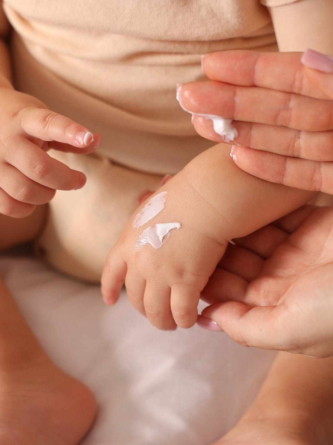 Parent applying cream to a baby's arm