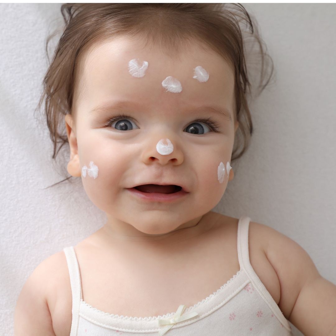 Smiling toddler with dots of fragrance-free moisturising cream on their face